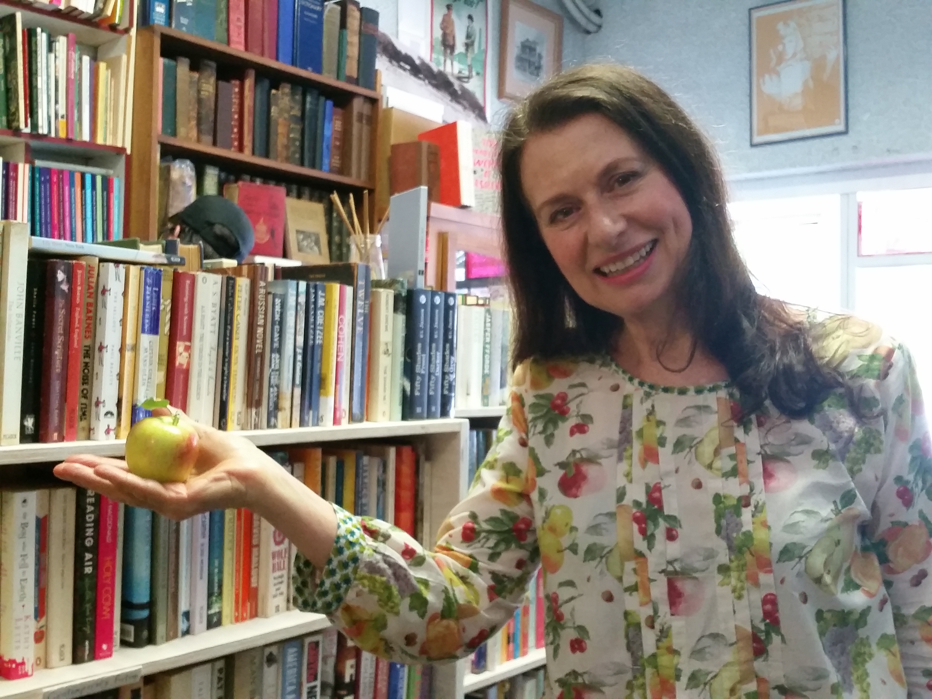 Suzie standing with a locally grown apple in Minerva's Bookstore
